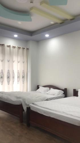 two beds in a room with a window at MOTEL Đồng Khởi in Giồng Tú Ðiền