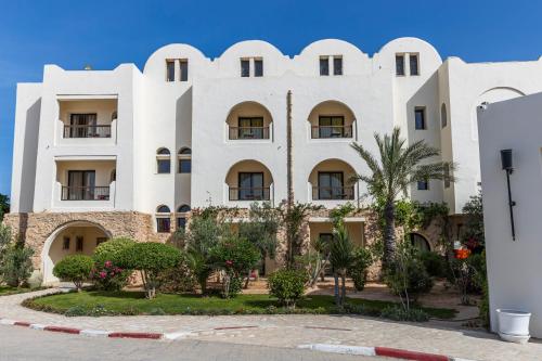 a large white building with trees in front of it at Le Petit Palais Djerba & Spa in Houmt Souk