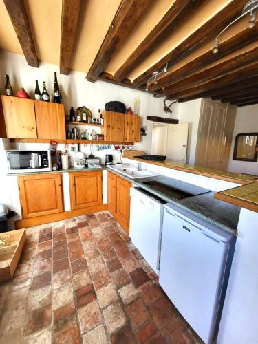 - une grande cuisine avec des placards en bois et des appareils blancs dans l'établissement Maison de campagne-jardin-wifi proche Beauval, à Villentrois