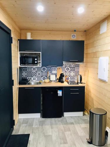 une cuisine avec des armoires noires et un comptoir dans l'établissement Le chalet de Lenny- spa- borne recharge- wifi, à Luçay-le-Mâle