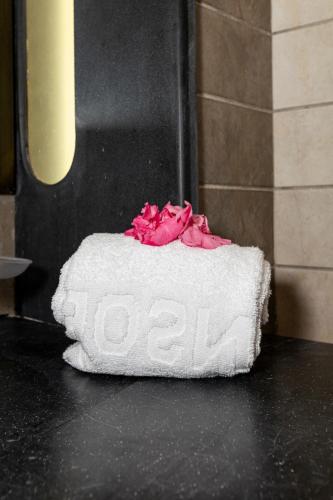 a white towel with pink flowers on top of it at Le Petit Palais Djerba & Spa in Houmt Souk