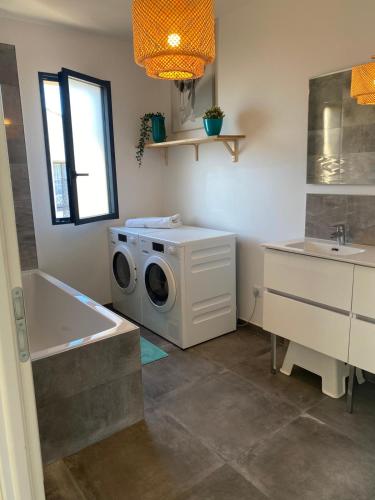 une salle de bain avec une machine à laver et un lavabo dans l'établissement Villa zen bord de mer, à Sète