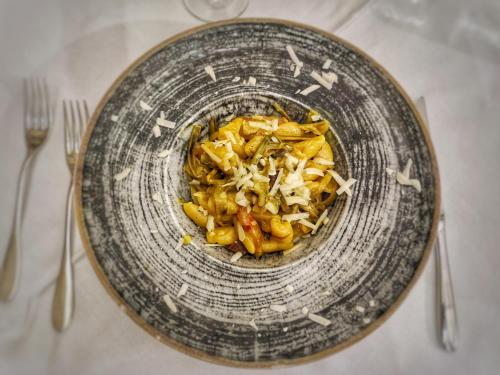 a bowl of food on a table with two forks at Palazzo Iaquinta - Rooms, Restaurant & Wellness in Cicerale