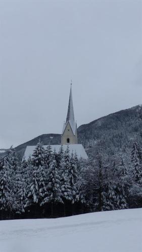 a church on top of a hill with snow covered trees at Multererhof in Nikolsdorf