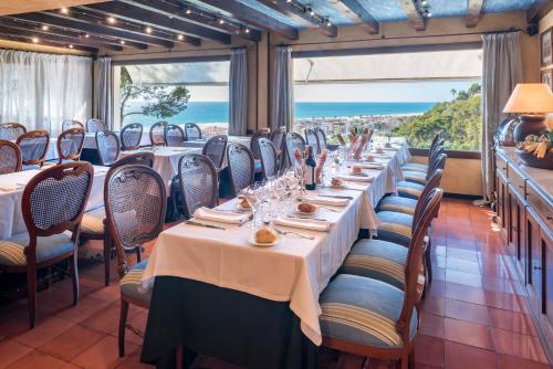 a dining room with tables and chairs with a view of the ocean at Gran Hotel Rey Don Jaime in Castelldefels