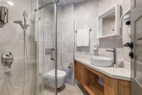 a bathroom with a toilet and a glass shower at Echinus Lara Hotel in Antalya