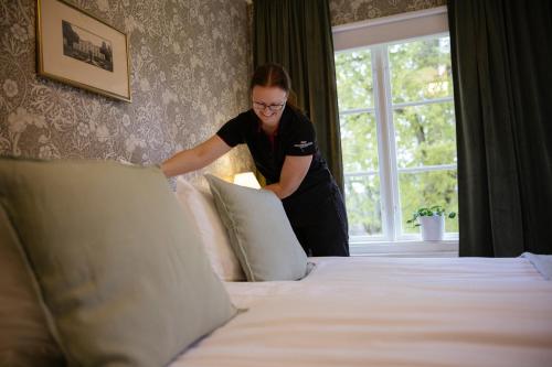 a woman in a hotel room making a bed at Asa Herrgård in Asa