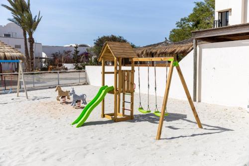 a playground with a swing set in the sand at Le Petit Palais Djerba & Spa in Houmt Souk