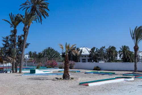 a beach with palm trees and surfboards on the sand at Le Petit Palais Djerba & Spa in Houmt Souk