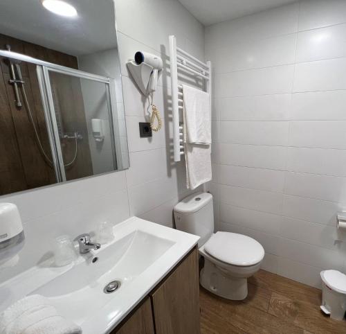 a white bathroom with a toilet and a sink at Hotel La Braña in San Isidro
