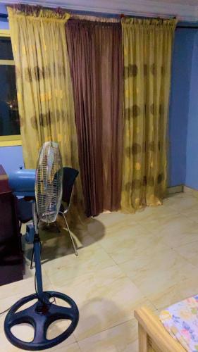 a room with a fan in a room with curtains at Service apartment in Kunkwaba