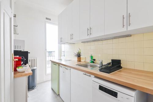 une cuisine avec des armoires blanches et un comptoir en bois dans l'établissement Élégant Studio Appartement Quartier Les Marais Free Netflix, à Paris