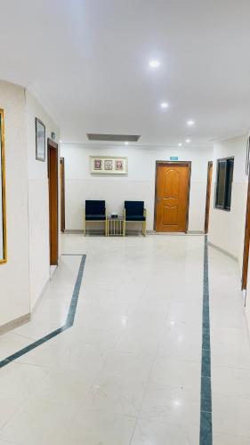 an empty hallway of a hospital with chairs and a door at Hotel New Mid City Multan in Multan