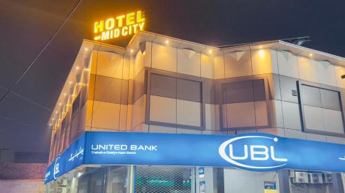 a hotel united bank building with a neon sign at Hotel New Mid City Multan in Multan