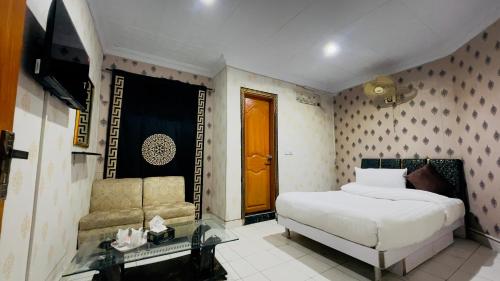 a bedroom with a bed and a couch and a television at Hotel New Mid City Multan in Multan