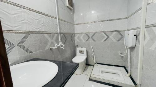 a small bathroom with a toilet and a sink at Hotel New Mid City Multan in Multan