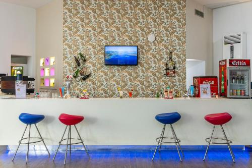 a bar with three red stools and a tv on a wall at Le Petit Palais Djerba & Spa in Houmt Souk