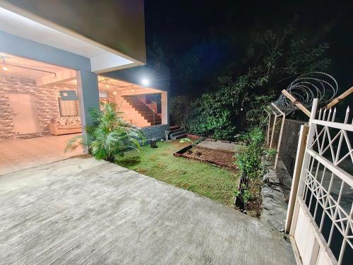 a house with a porch and a fence at night at Boom Party Villa in Pirangut
