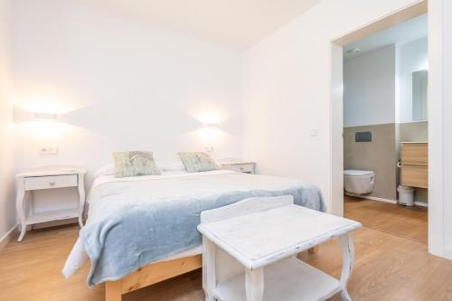 a white bedroom with a bed and a stool at Ses Set Tanques de Son Fosquet in Llucmajor