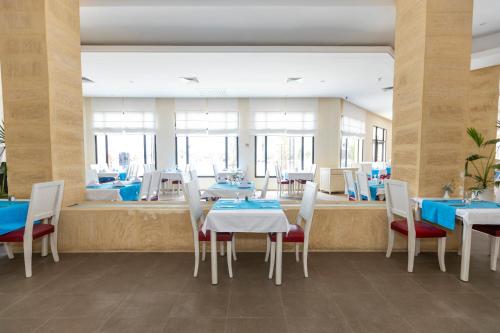 a dining room with white tables and chairs and blue tables at Le Petit Palais Djerba & Spa in Houmt Souk