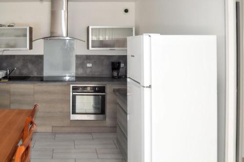 a kitchen with a white refrigerator and a table at Maison charmante à Saint-Georges-de-Didonne avec jardin in Saint-Georges-de-Didonne