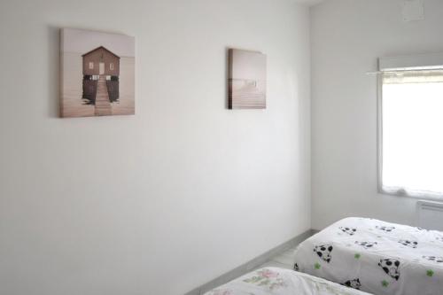 - 2 lits dans une chambre avec 2 photos sur le mur dans l'établissement Maison charmante à Saint-Georges-de-Didonne avec jardin, à Saint-Georges-de-Didonne