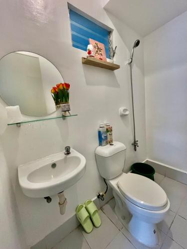 a bathroom with a white toilet and a sink at Loven Transient House in Dauis