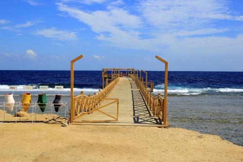 a wooden boardwalk leading to the ocean on a beach at Beach safari nubian resort in Marsa Alam City