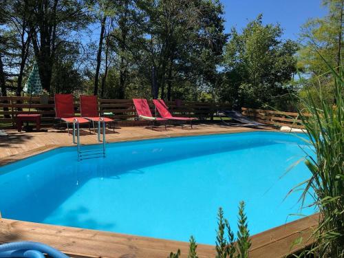a swimming pool with red chairs and a bench at Les Lodges de Phanou in Prissac