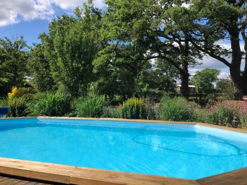 a swimming pool in a garden with trees at Les Lodges de Phanou in Prissac