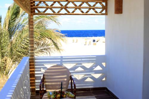 a chair sitting on a porch looking out at the beach at Beach safari nubian resort in Marsa Alam City