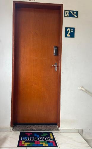 a brown door with a welcome mat in front of it at Confortável Apartamento in Pouso Alegre