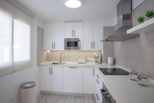a white kitchen with a sink and a microwave at New! Renovated Flat In Mijas in Mijas