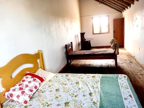 a bedroom with a bed and a chair and a window at Casa da família Castro in Capão da Canoa
