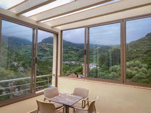 a table and chairs in a room with windows at appartements Al Amri akchour in Chefchaouene