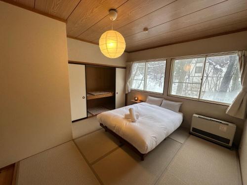 una camera con letto bianco in una stanza con finestre di Hakuba Third Place Lodge a Hakuba