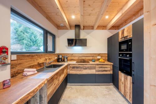 une cuisine avec des comptoirs en bois et une fenêtre dans l'établissement Chalet L'Echappée Belle, luxury with spa and sauna, à Xonrupt-Longemer