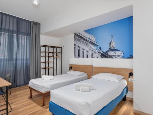 two beds in a room with a picture of a building at B&B HOTEL Milano Ornato in Milan