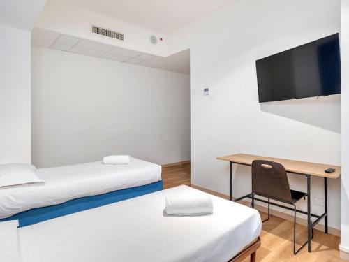 a room with two beds and a desk and a tv at B&B HOTEL Milano Ornato in Milan