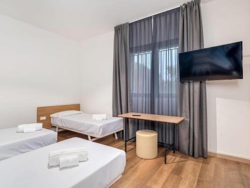a room with two beds and a flat screen tv at B&B HOTEL Milano Ornato in Milan