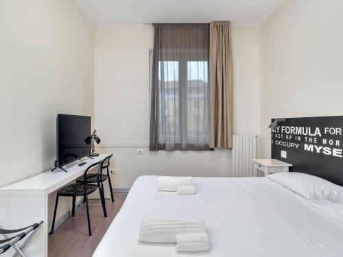 a white room with a bed and a desk and a tv at B&B HOTEL Milano Ornato in Milan
