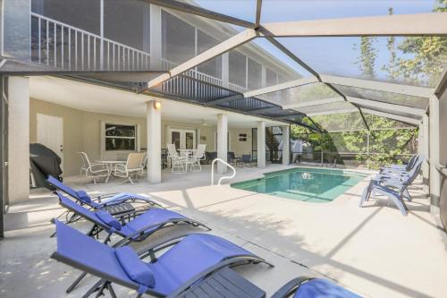 a house with a swimming pool with blue lounge chairs at Coconut Palm House in Captiva