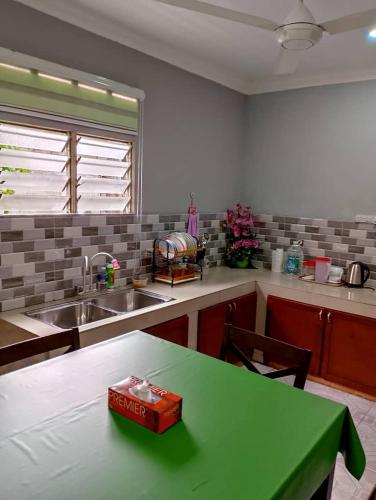 a kitchen with a green table with a box on it at D'Maryam Homestay in Muar