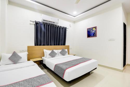 une chambre avec deux lits et une fenêtre dans l'établissement Super Townhouse De Alphabet Kukatpally Near Nexus Mall, à Hyderabad