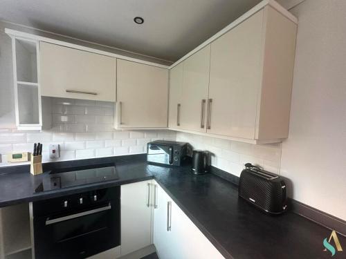 a kitchen with white cabinets and black appliances at Overton View in Stockton-on-Tees