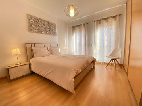 a bedroom with a large bed with white sheets and wooden floors at Am Hafen - House Barbara 1 l Marina Olhão in Olhão