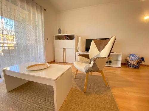a living room with a white chair and a table at Am Hafen - House Barbara 1 l Marina Olhão in Olhão