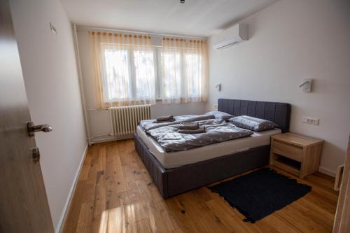 a bedroom with a bed and a window and wooden floors at FIVE apartment - very center in Osijek