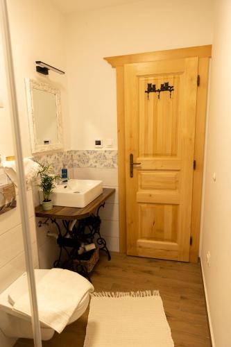 a bathroom with a sink and a wooden door at Neidhardt Vendégház in Bóly