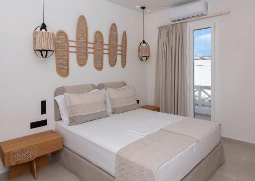 a white bedroom with a bed and a balcony at Aristotle Suites in Adamas